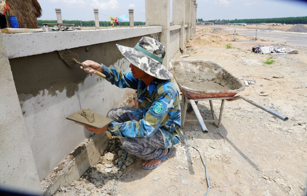 Một công nhân đang dặm vá tường bao Trường mầm non ở khu tái định cư Lộc An - Bình Sơn